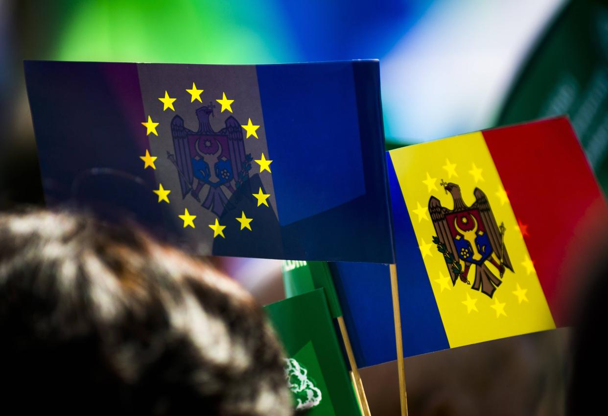 Moldovan and European Union flags displayed side by side at a public gathering.
