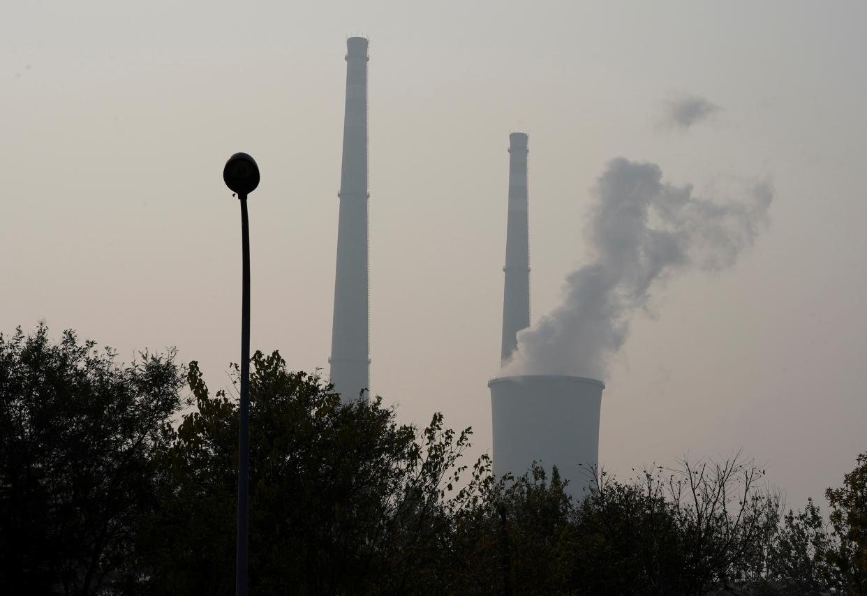A cooling tower and chimneys are seen at a thermal power plant on a polluted day in Beijing