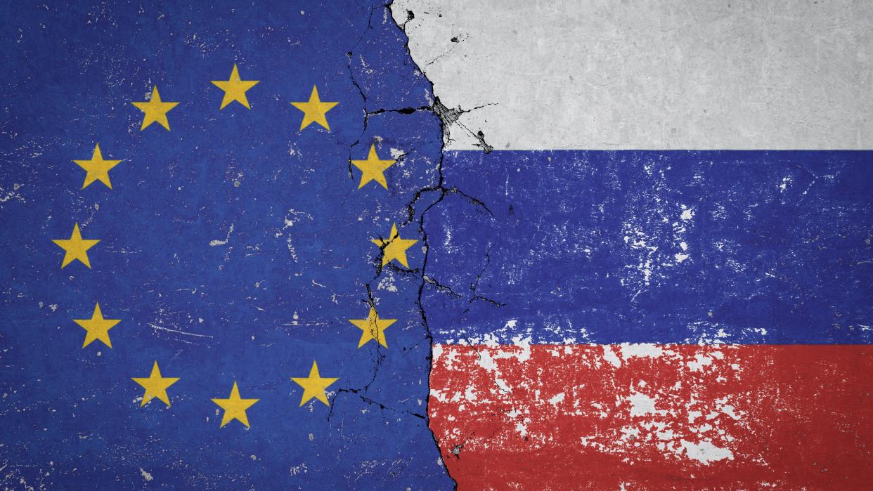 Flagge Russlands und Flagge der Europäischen Union an einer alten beschädigten Mauer