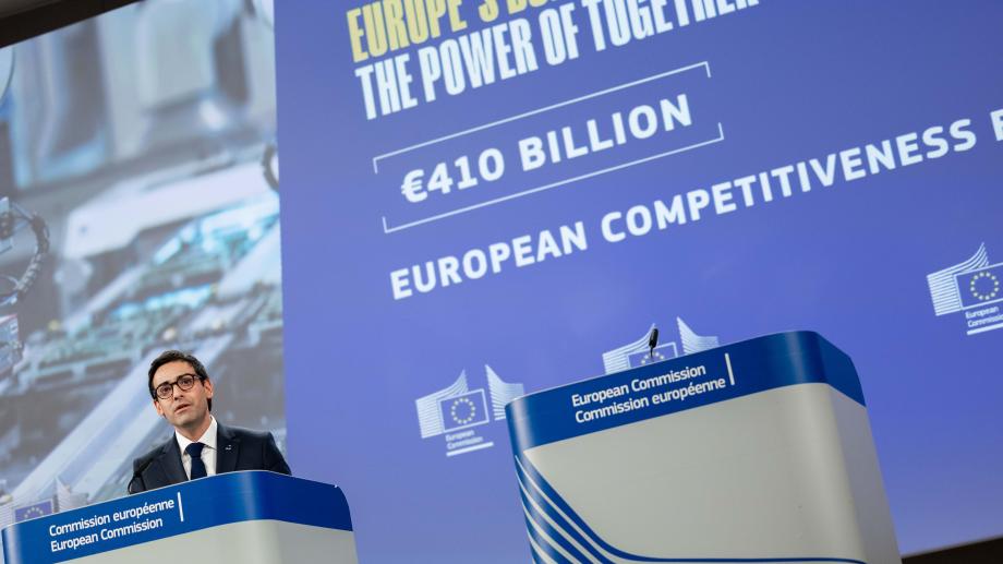 Stéphane Séjourné speaks at a European Commission podium in front of a screen displaying information on the EU budget and European competitiveness.