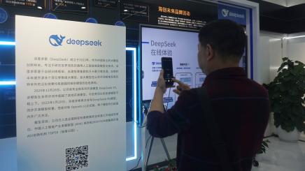 A visitor uses a smartphone in front of a DeepSeek AI display at an exhibition in Hangzhou, China.