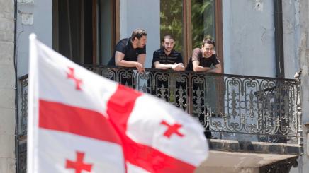 Bild: drei junge Männer schausen sich in Tiflis eine Militärparade an