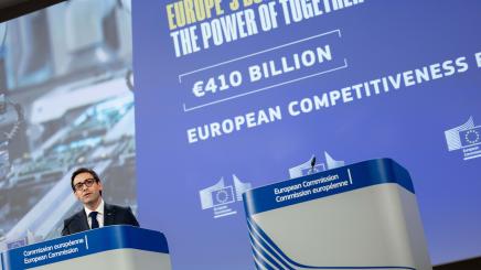 Stéphane Séjourné speaks at a European Commission podium in front of a screen displaying information on the EU budget and European competitiveness.