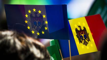 Moldovan and European Union flags displayed side by side at a public gathering.